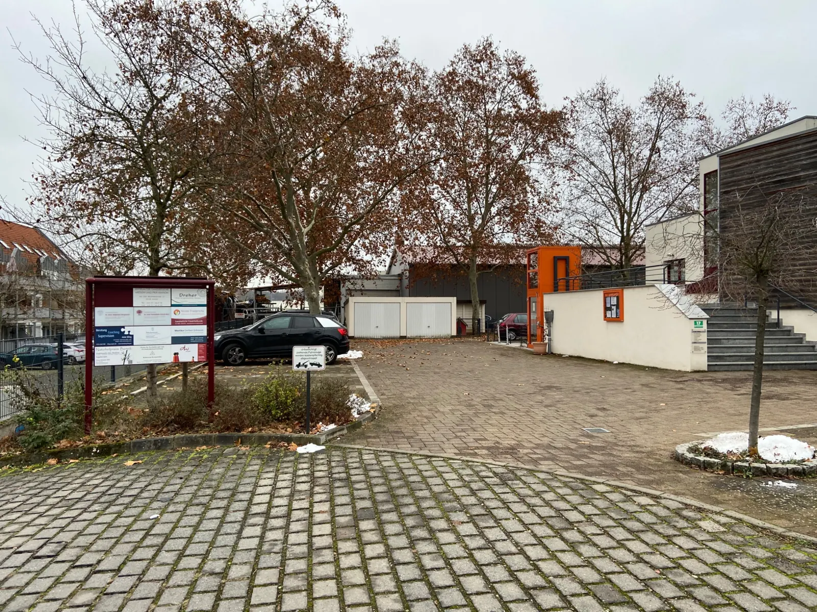 Zufahrt zur Brunnenstube 17 mit Parkplatz und orangefarbenem Außenaufzug rechts am Gebäude
